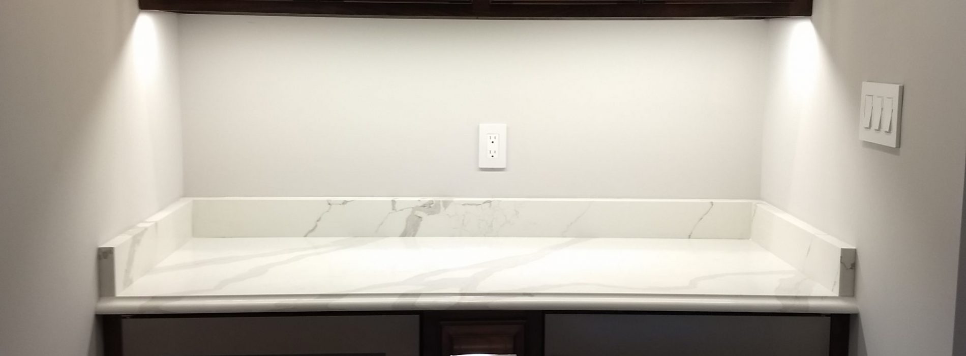marble counter with dark wood cabinets for plates or drinks