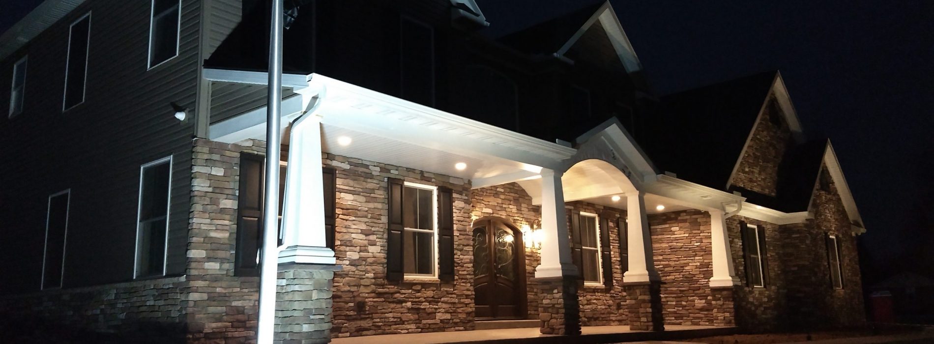 night time view of the grey and maroon house front porch